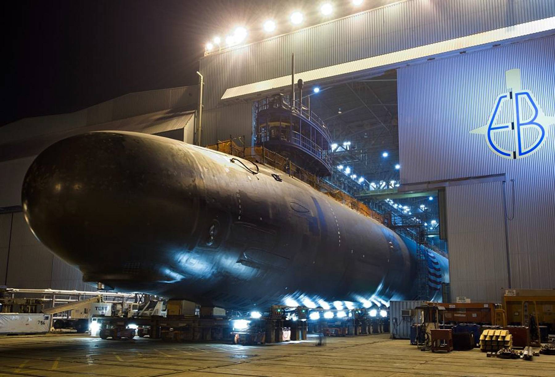 A submarine under construction at an Electric Boat shipyard in Groton, Connecticut, with workers on scaffolding in the manufacturing facility