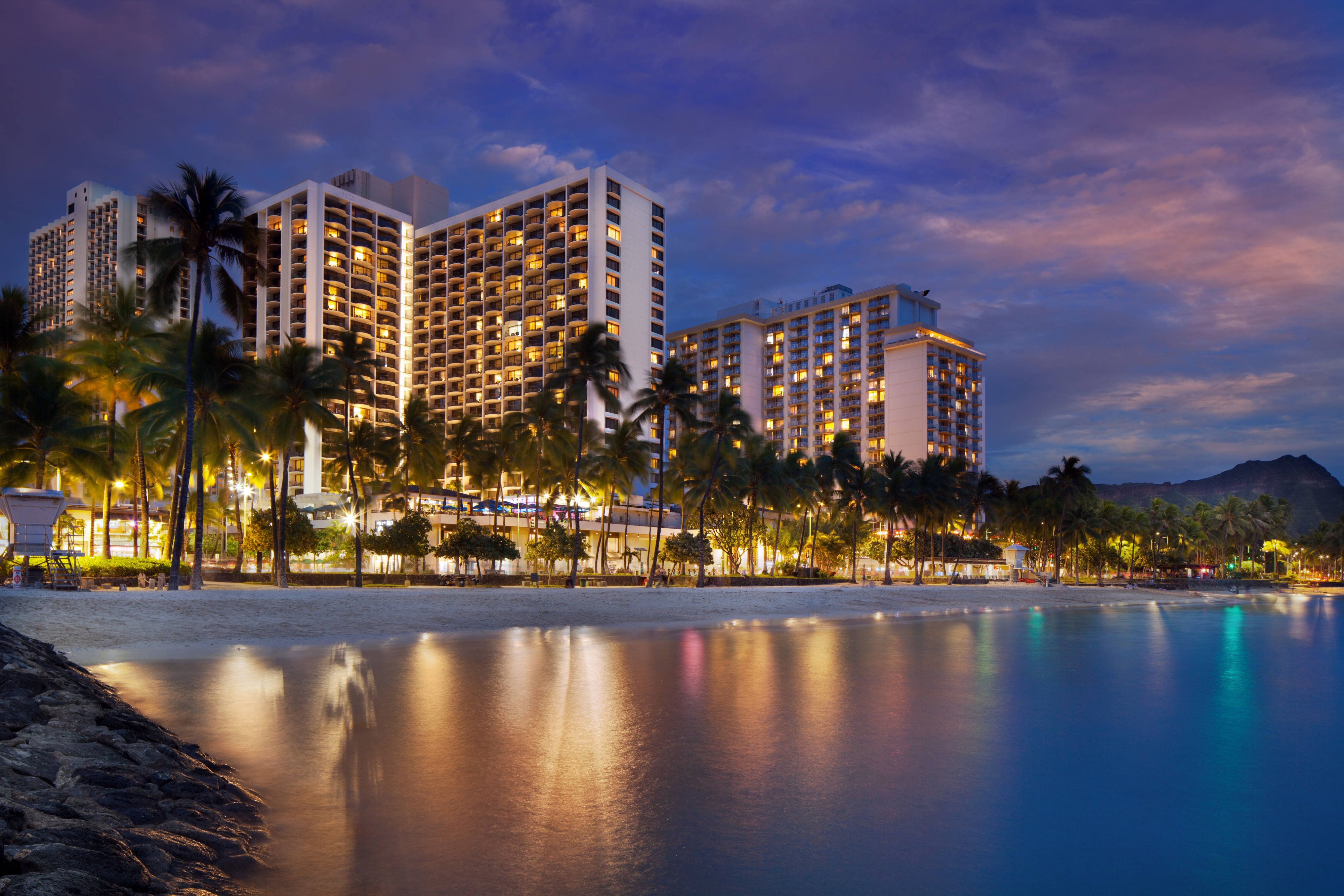 Waikiki Beach lined with resort hotels and palm trees along the turquoise Pacific Ocean shoreline on the island of Oahu